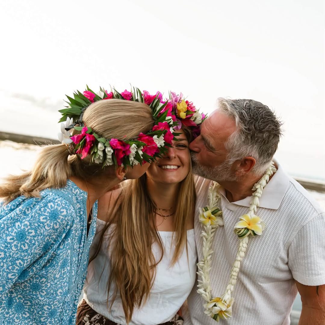 Parents qui embrassent leur fille, colliers de fleurs