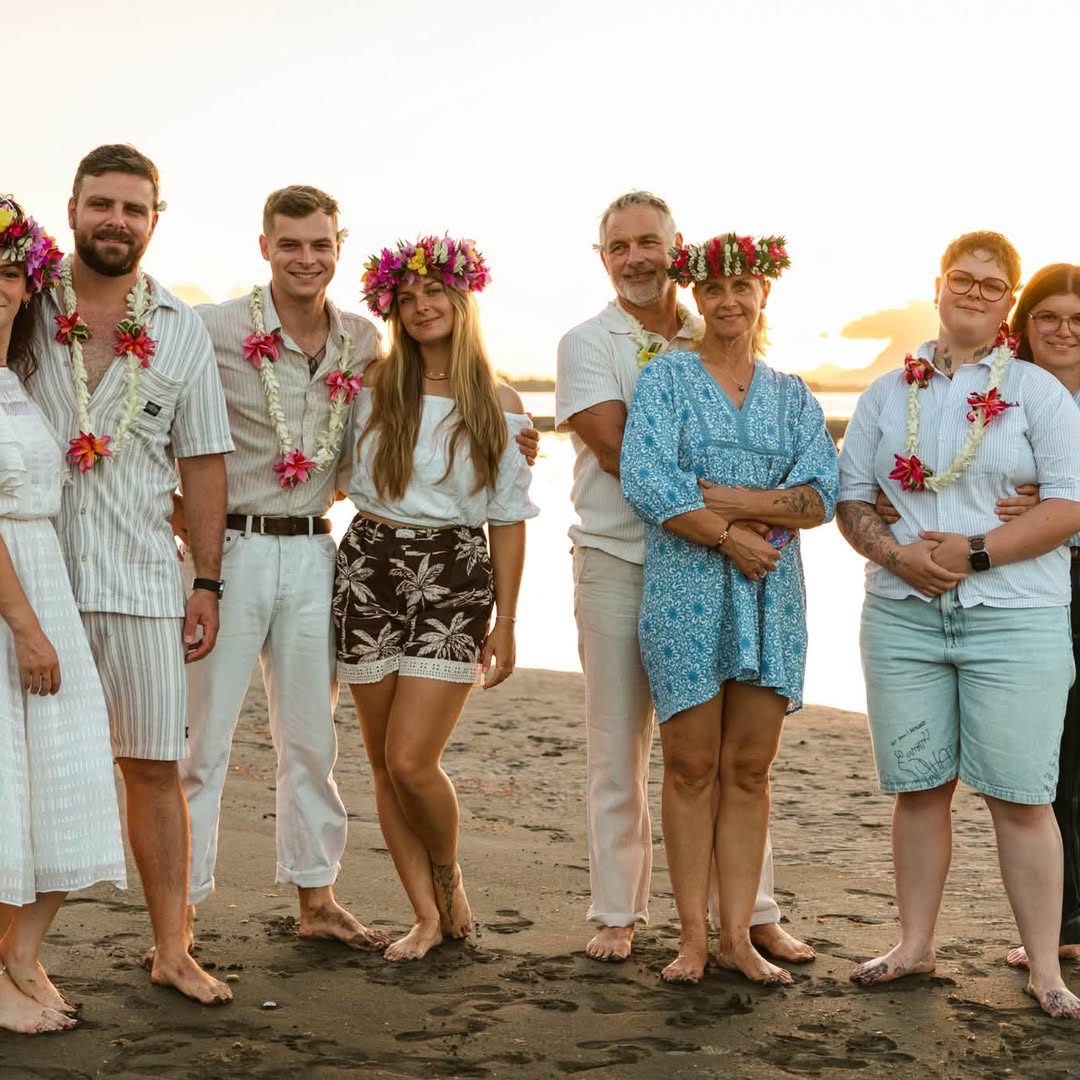 Grande famille réunie en couronnes de fleurs sur une plage au coucher du soleil