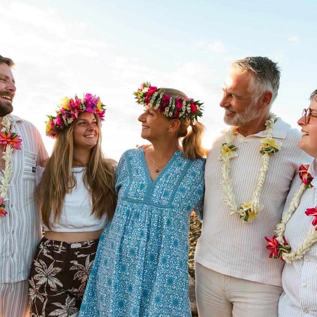 Famille couronnée de fleurs qui rit au coucher du soleil sur la plage